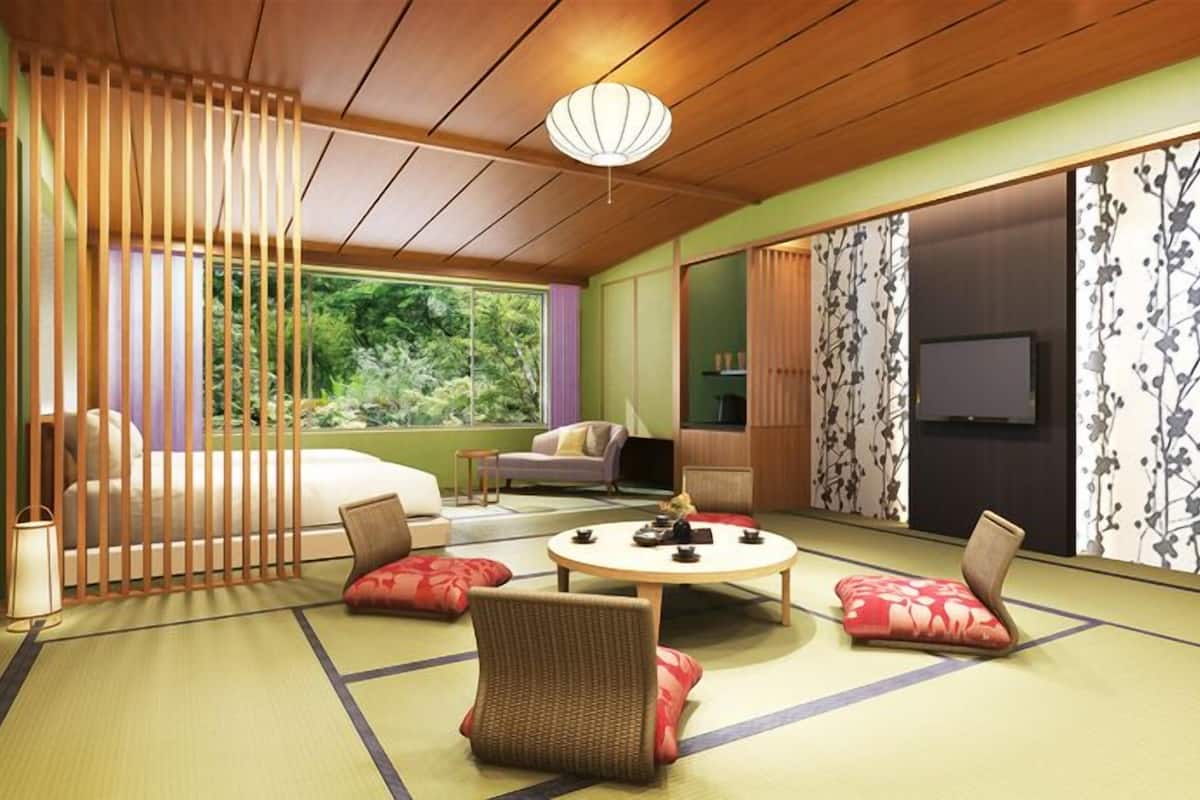 A traditional Japanese room with tatami flooring, a low table, cushions, sliding doors, and a ceiling light fixture.
