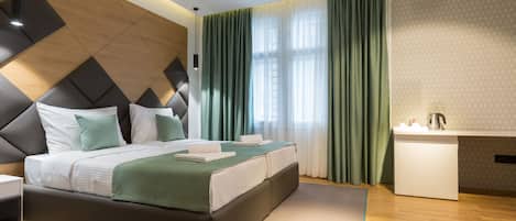 Et moderne hotelværelse med en stor seng, et sengebord, et indbygget skrivebord og et badeværelse med vask og spejl.