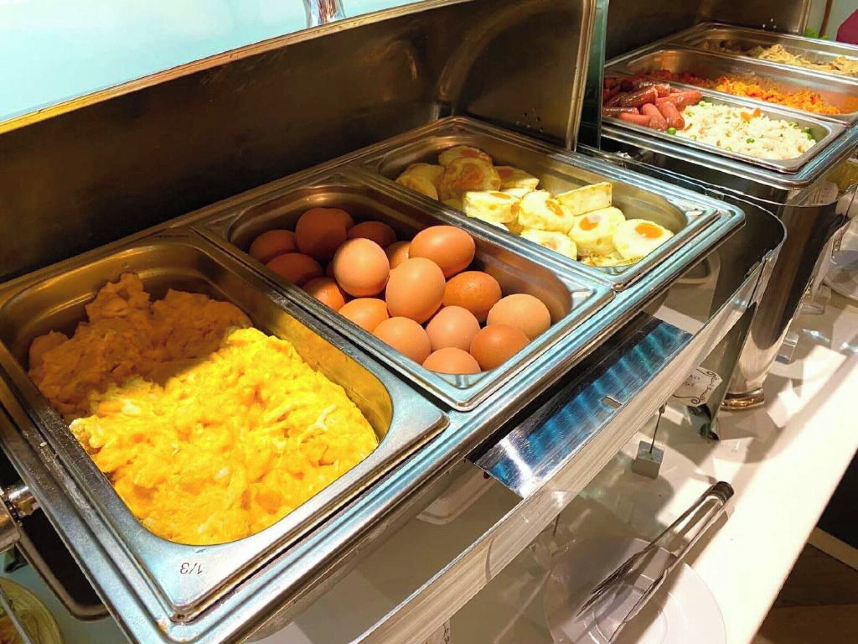 Un buffet proposant une variété de plats, notamment des œufs, des pommes de terre et d’autres mets.