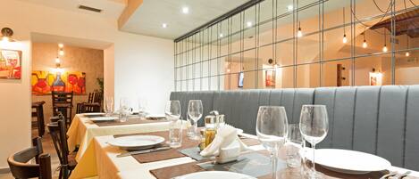 A restaurant interior with tables set for dining, a large window with a view, and a modern design.