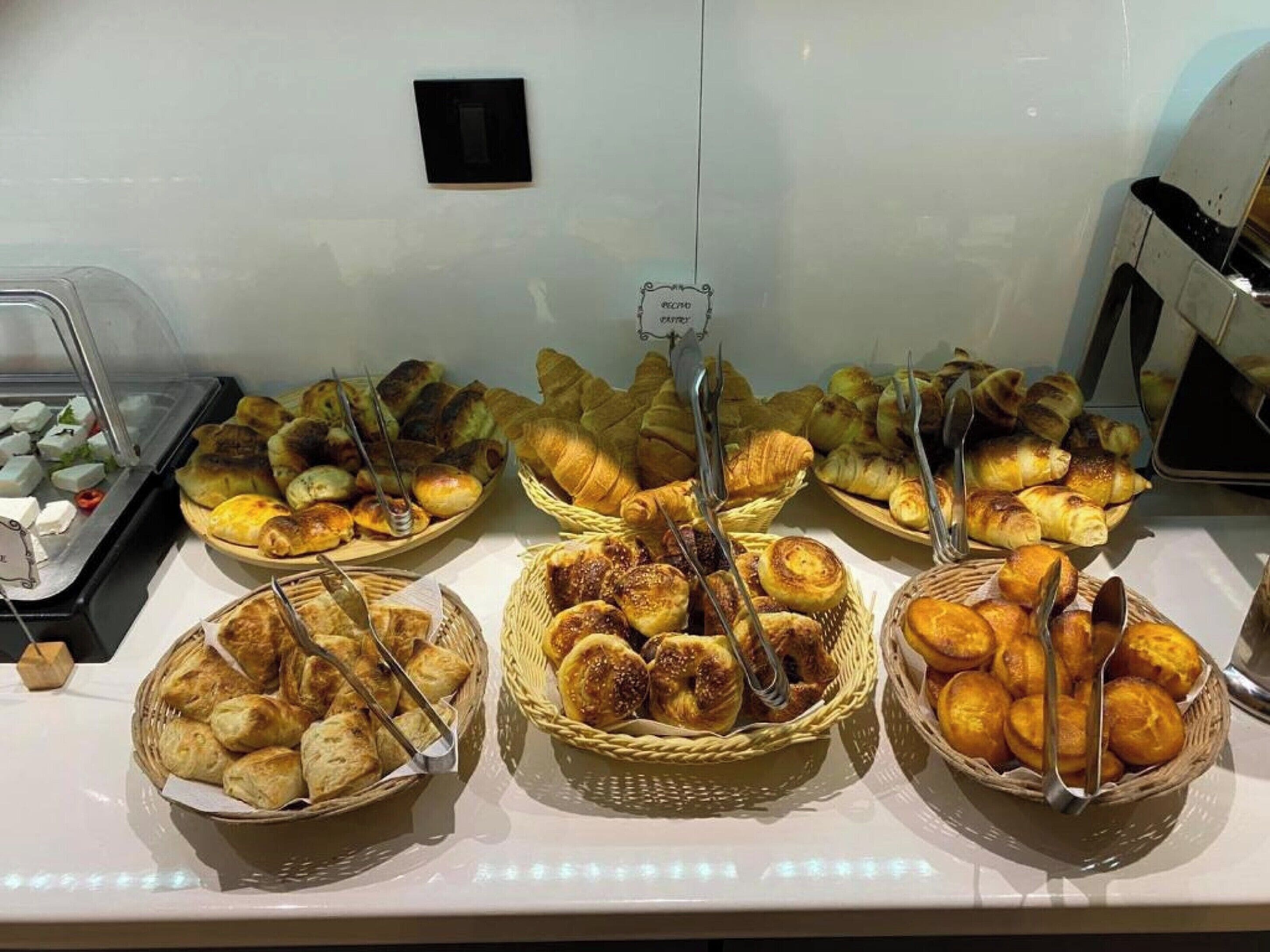 A buffet with various baked goods including pastries and bread.