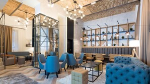 A modern lounge area with blue and beige seating, a geometric patterned floor, and a brick ceiling. - Hotel Capital (Belgrade)