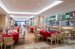 Un comedor espacioso con mesas redondas cubiertas con manteles rojos, dispuestas en forma de U.