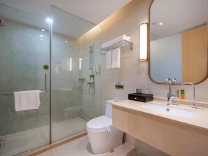 Un baño moderno con ducha de vidrio, inodoro blanco y lavamanos con espejo.