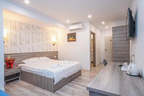 Una camera d'albergo moderna con un letto, un comodino, una TV e un angolo cottura.