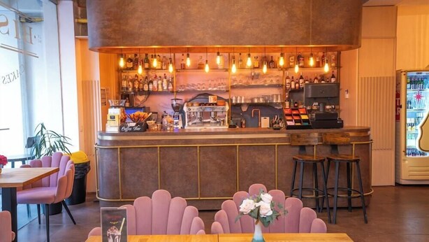 A bar area with a counter, stools, and a coffee machine.