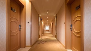 A hotel hallway with doors marked with room numbers, a carpeted floor, and a ceiling with recessed lighting. - Vienna Hotel Foshan Nanhai Avenue Branch (Foshan)