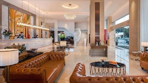 A spacious lobby with a reception desk, leather seating, a staircase, and large windows. - Vienna Hotel Foshan Nanhai Avenue Branch (Foshan)