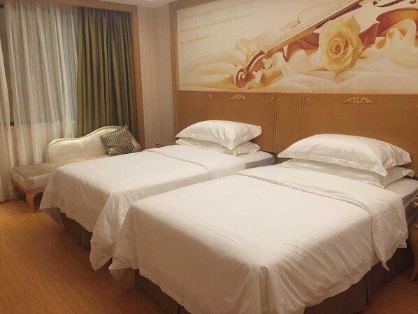 Une chambre d’hôtel avec deux lits, un banc et une grande fresque murale représentant des motifs floraux.