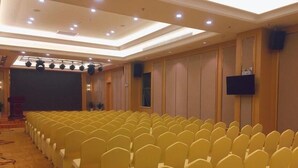 A conference room with rows of yellow chairs, a podium, and a large screen. - Vienna Hotel Foshan Nanhai Avenue Branch (Foshan)