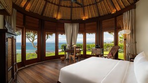 Une chambre spacieuse avec un grand lit, un plancher en bois et une vue sur l’océan.