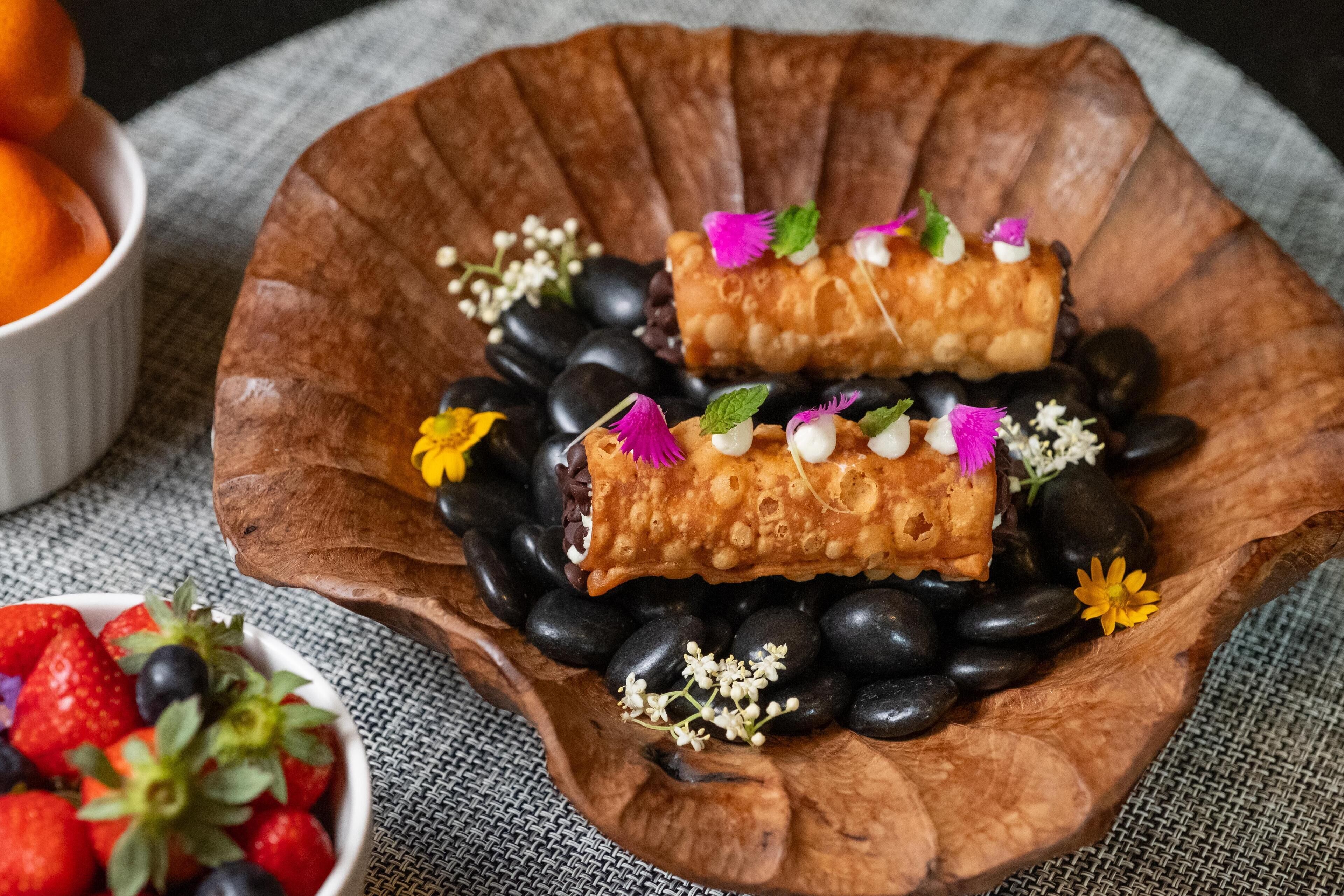 A wooden bowl with pastries and berries.