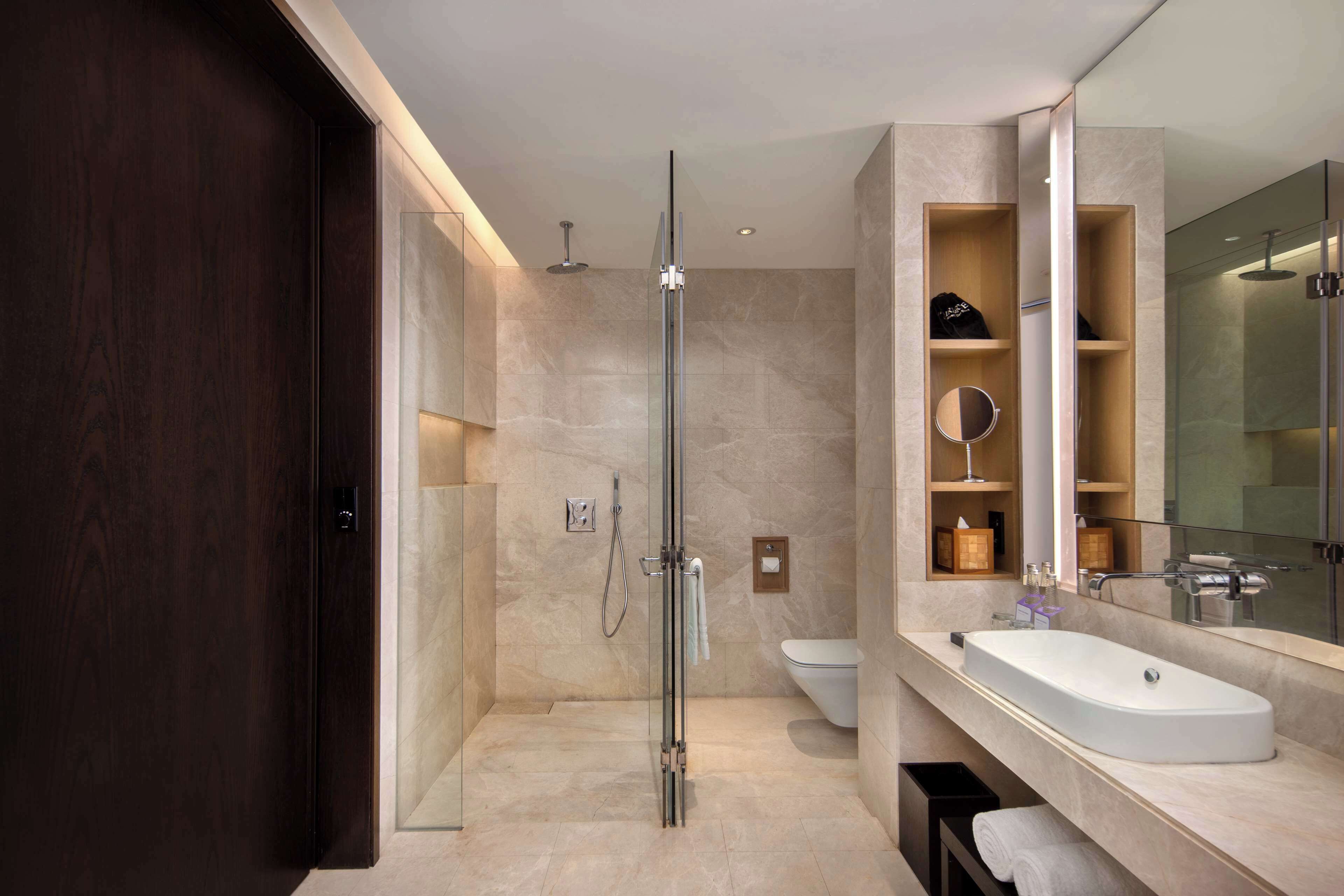Une salle de bain moderne avec une douche à parois de verre, un grand miroir et un meuble-lavabo.