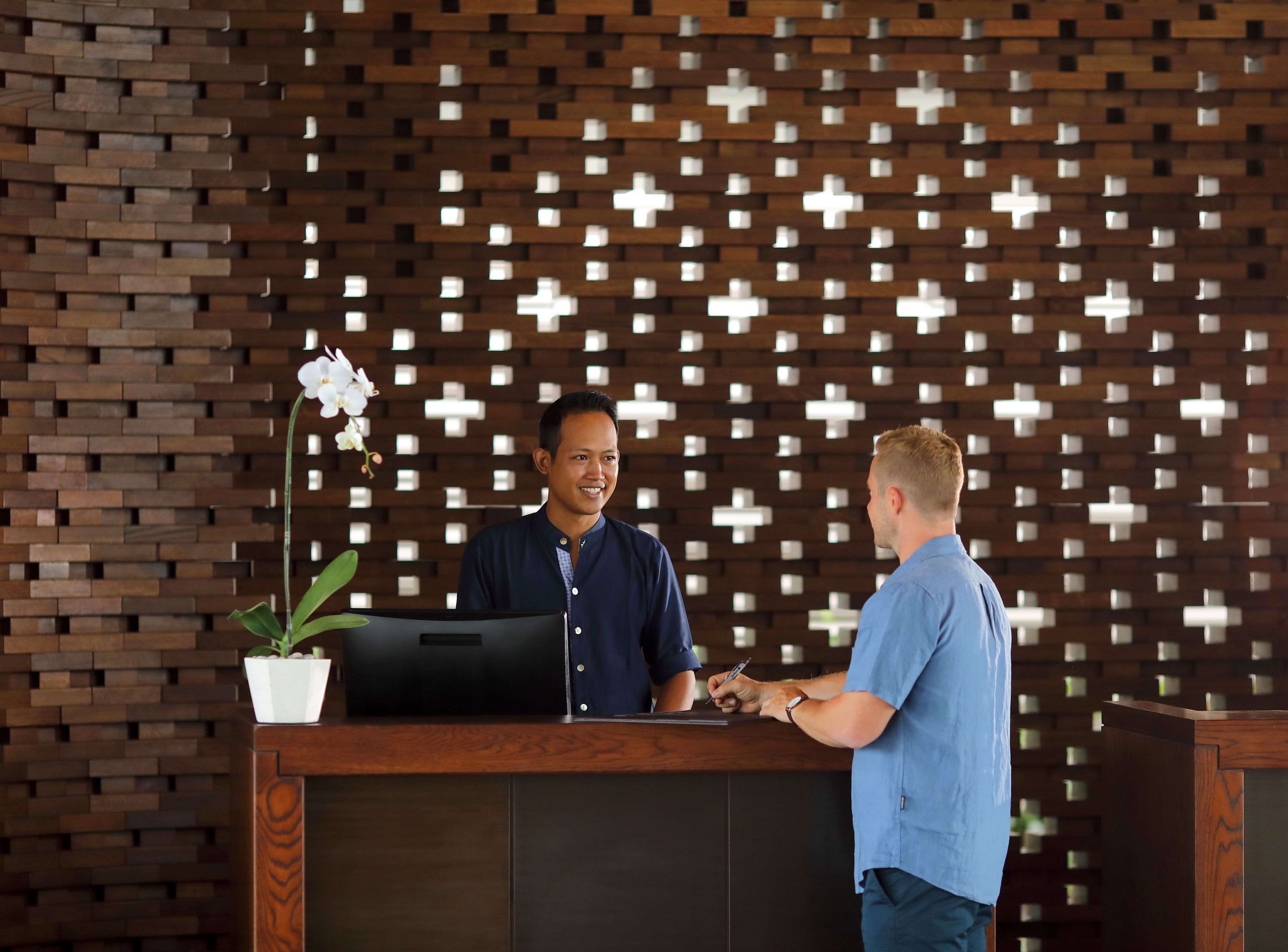 Un comptoir d’accueil agrémenté d’un mur en briques au design moderne et d’un motif décoratif.