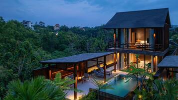 A modern house with a pool, surrounded by lush greenery.