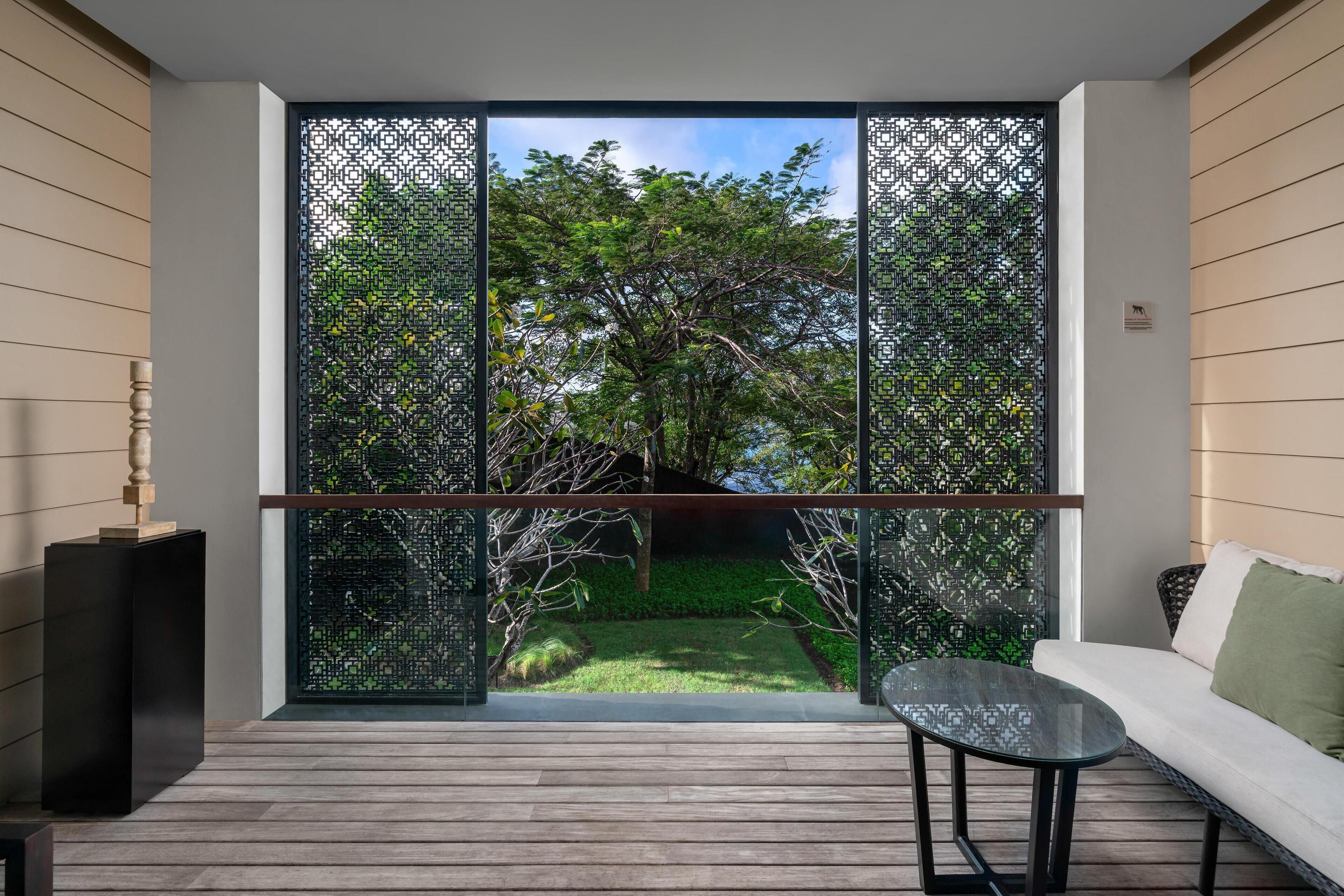 A modern room with a glass partition, a wooden floor, a glass table, and a white sofa.