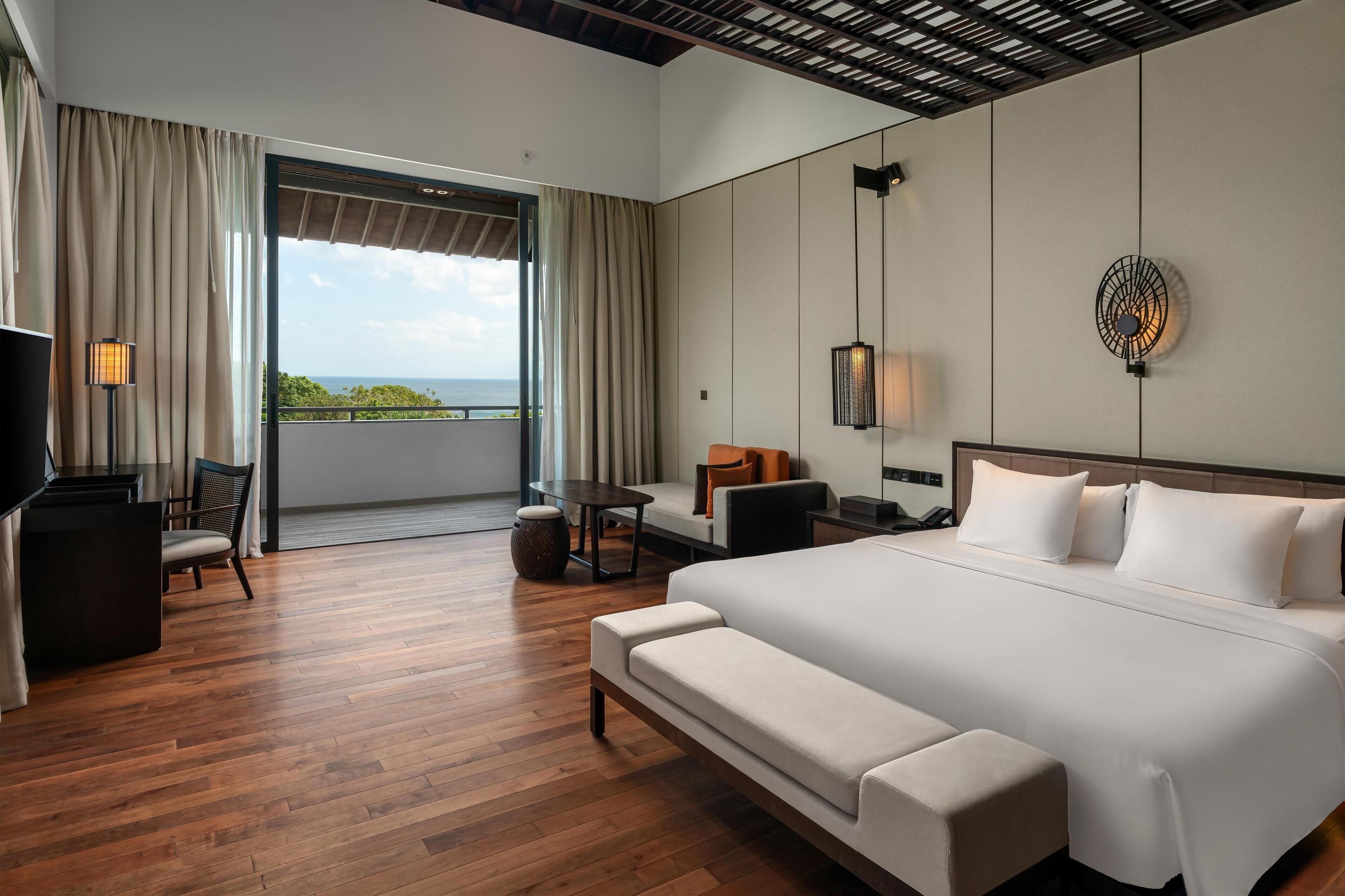 Een moderne hotelkamer met een groot bed, een bank, een bureau en uitzicht op de omgeving.