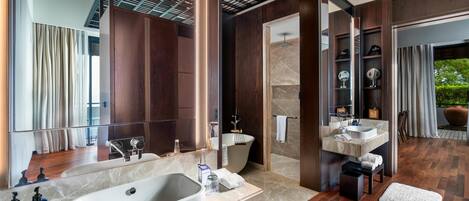 A modern bathroom with a large bathtub, dual sinks, and a vanity area.
