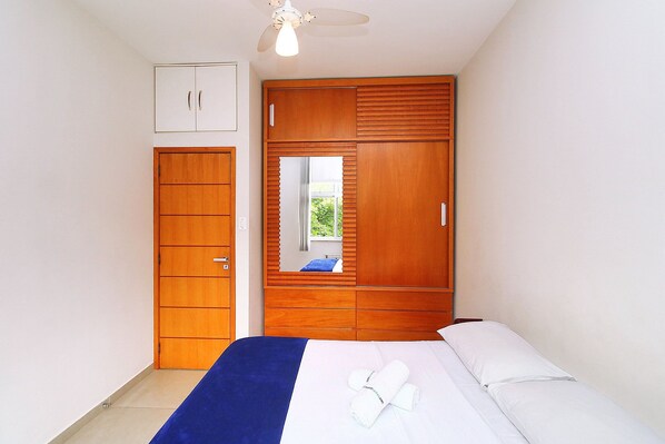 A bedroom with a bed, a wardrobe, and a mirror.