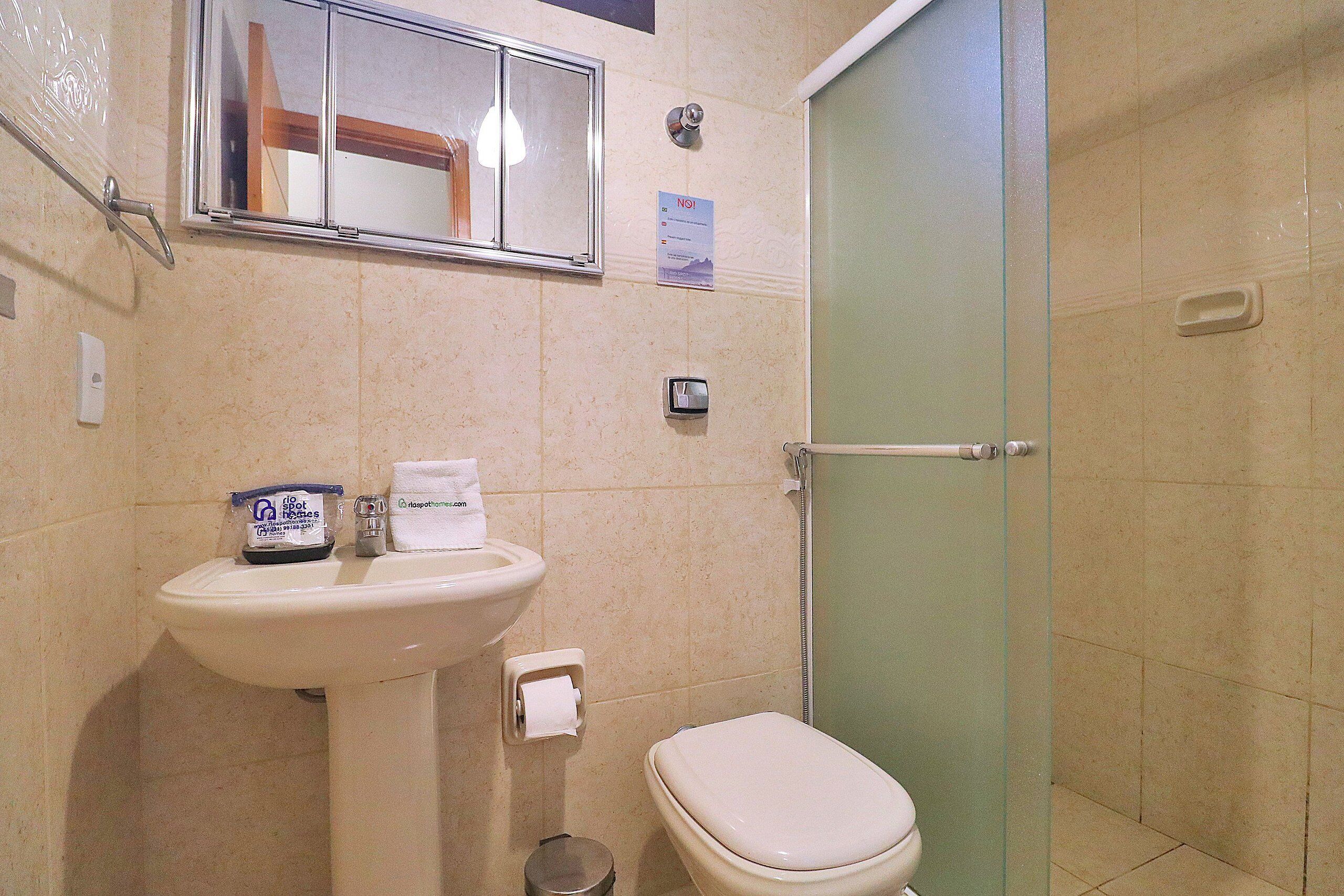 Ein Badezimmer mit Waschbecken, Toilette und einer Duschkabine aus Glas.