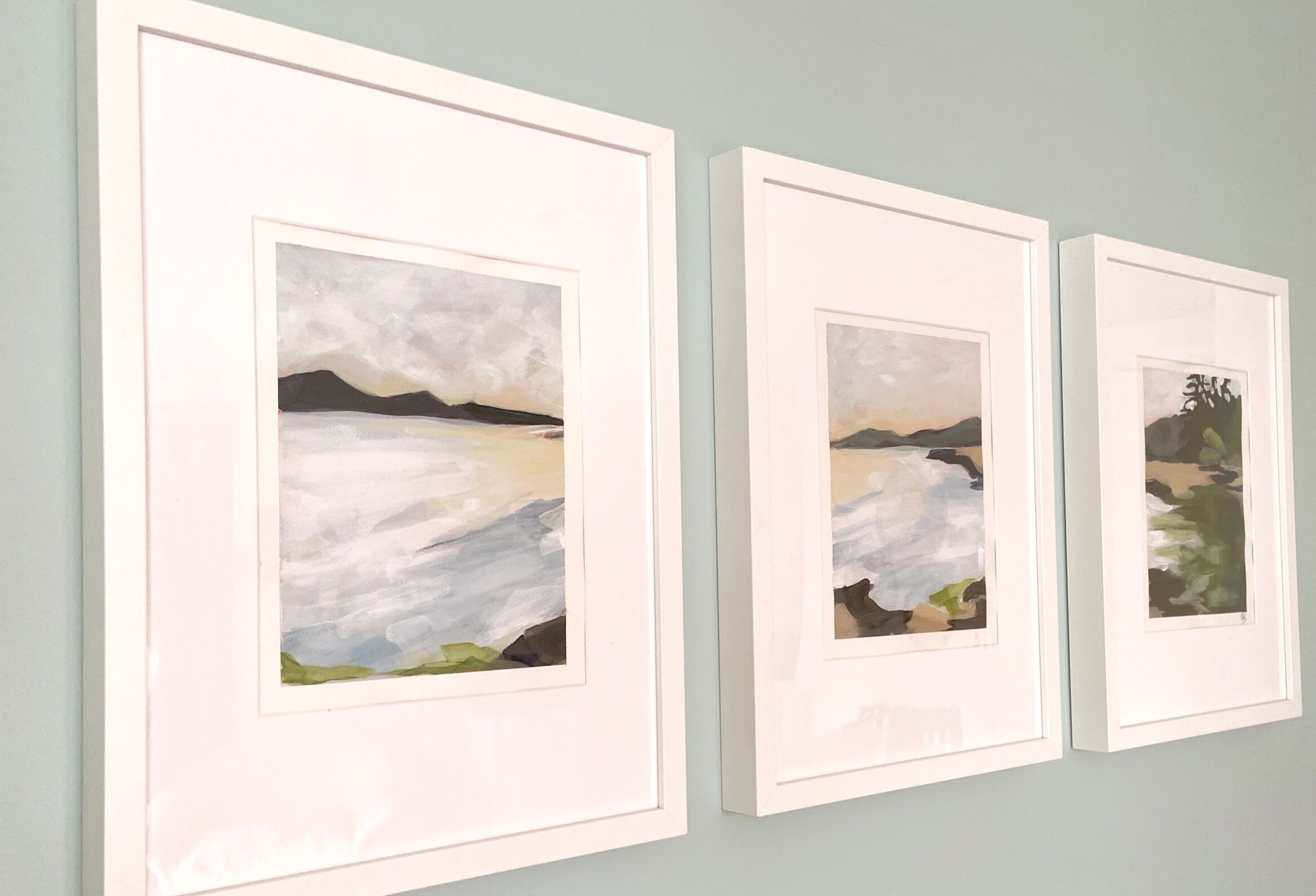 Trois œuvres d’art encadrées sont accrochées au mur.