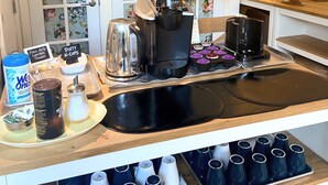 A coffee station with a coffee maker, tea kettle, and various cups and mugs. - Wisteria Guest House (Salt Spring Island)