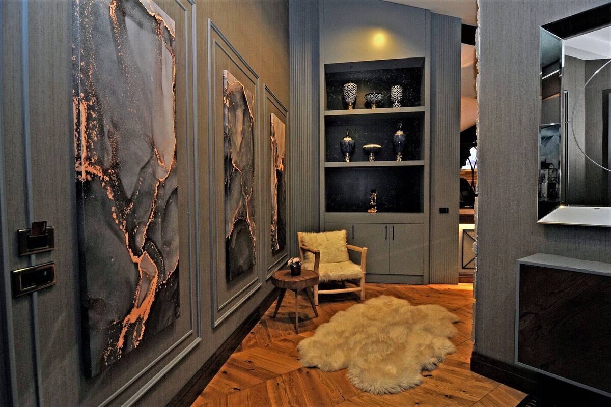 A modern interior with a wooden floor, a fur rug, a wooden chair, and a shelf with decorative items.