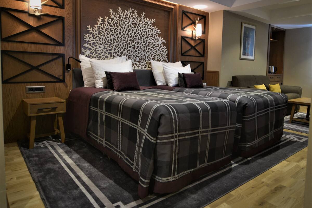 A modern bedroom with a large bed, a decorative headboard, and a small bedside table.