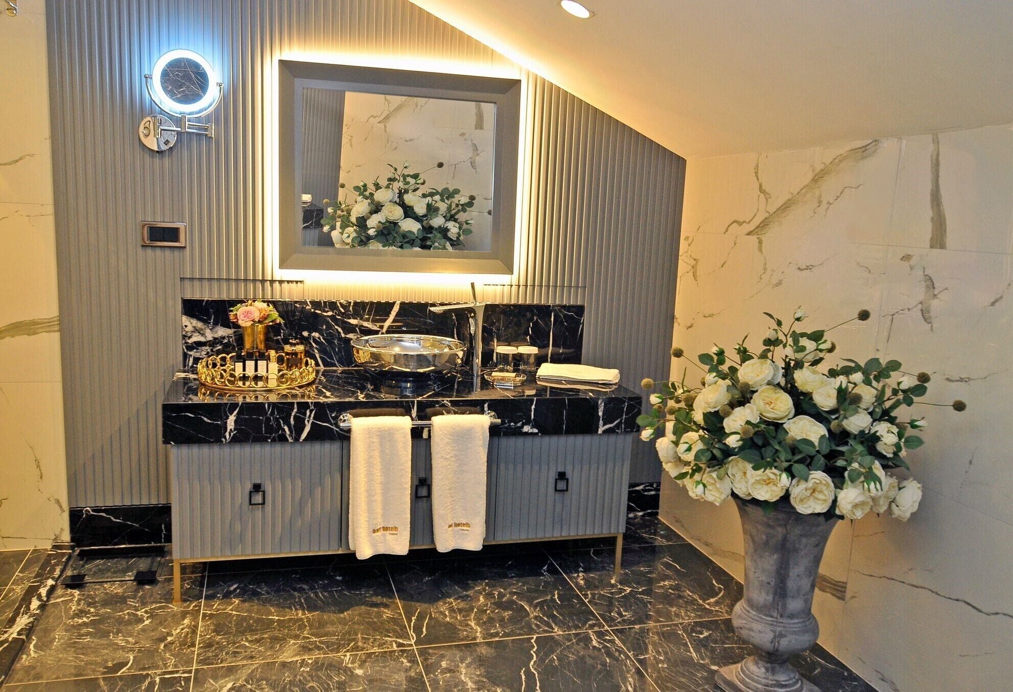A modern bathroom with a vanity, a mirror, and a vase of flowers.