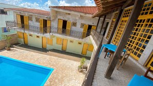 Un edificio residencial con piscina, balcones con barandillas y un patio con baldosas.