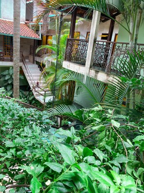 Ein mehrgeschossiges Gebäude mit Balkonen, umgeben von üppiger Vegetation und tropischen Pflanzen.