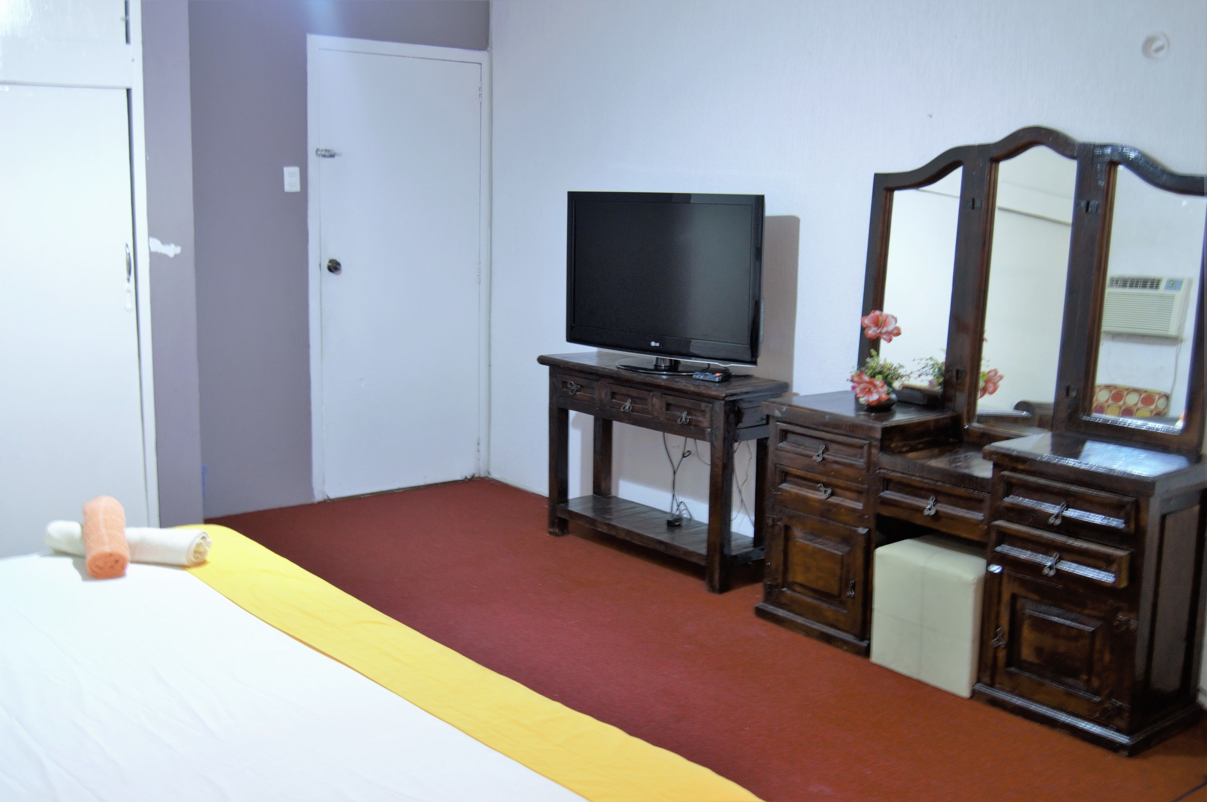 Una camera da letto con un letto, una cassettiera, un televisore e uno specchio.