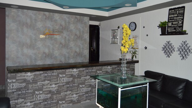A hotel reception area with a modern design, including a reception desk, a clock, and decorative wall art. - Hotel Jordan (Coatzacoalcos)