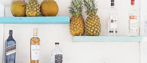 A shelf with various bottles and fruits.