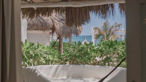 A doorway leading to a room with a view of a beach, a hammock, and some greenery. - Coco Unlimited (Tulum)