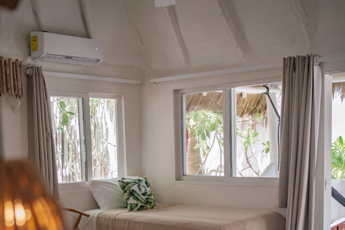 Un dormitorio con dos camas, ventilador de techo, aire acondicionado y ventanas con cortinas.