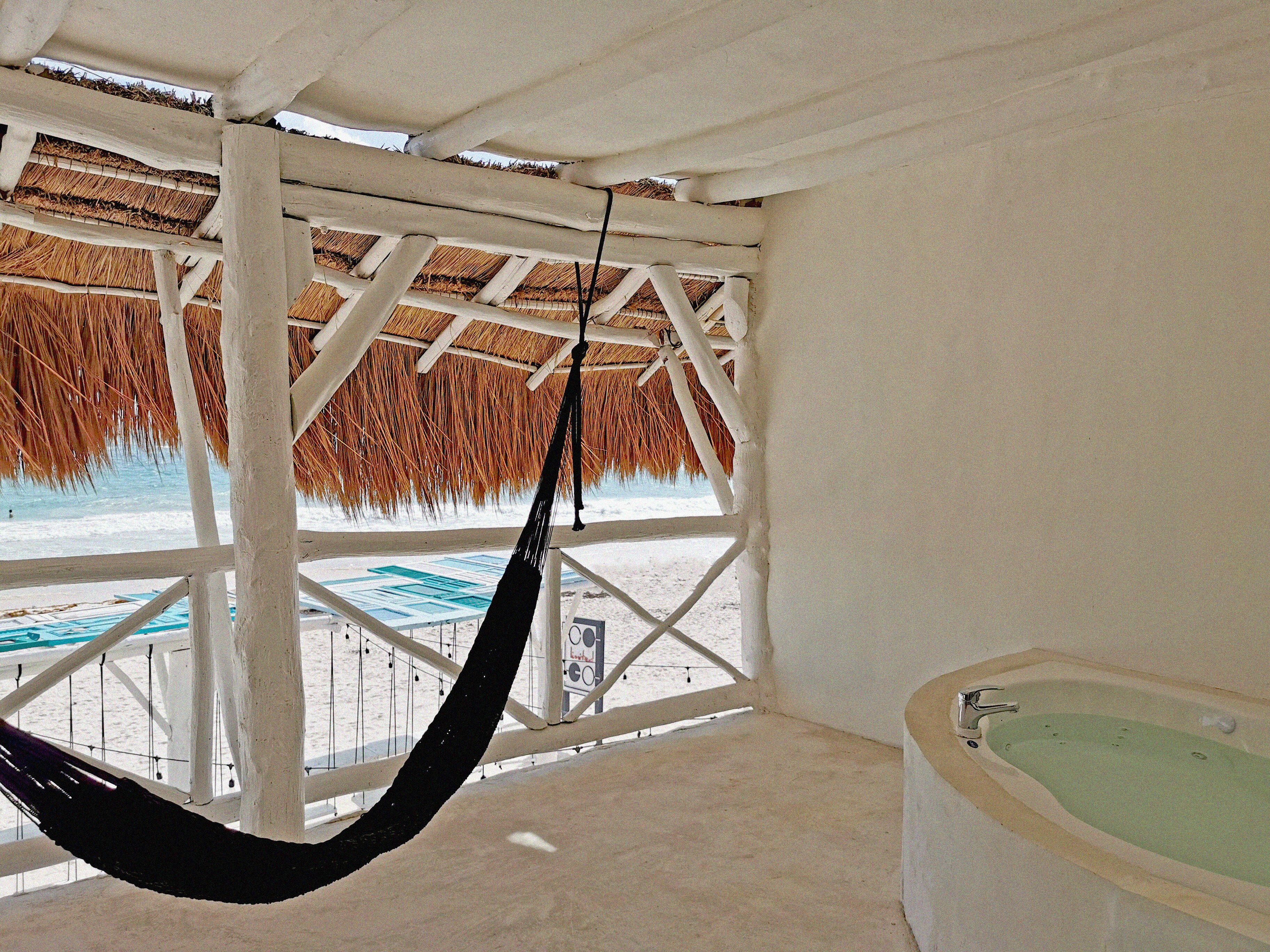 A beachside room with a hammock, a bathtub, and a view of the beach.