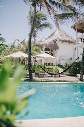 Una piscina al aire libre, sillones reclinables de piscina