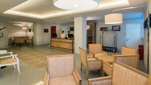 A hotel lobby with a reception desk, seating area, and a large chandelier. - Yans House Hotel Bali (Kuta)