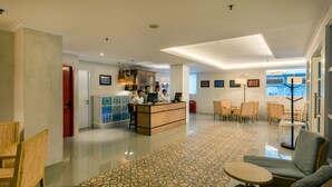 A hotel lobby with a reception desk, seating area, and a patterned carpet. - Yans House Hotel Bali (Kuta)