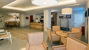 A hotel lobby with a reception desk, seating area, and a large chandelier. - Yans House Hotel Bali (Kuta)