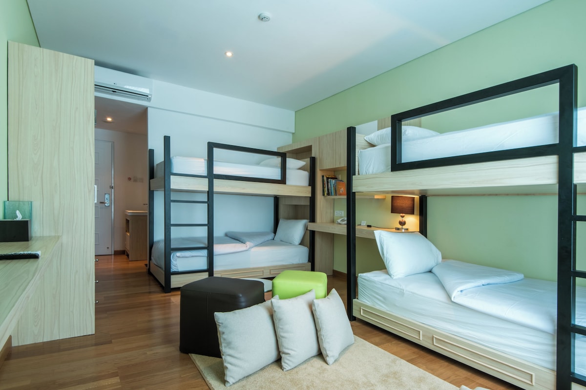 A compact room with bunk beds, a desk, and a small kitchenette.