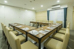 A conference room with a long table, chairs, and a window with curtains. - Yan's House Hotel (Kuta)
