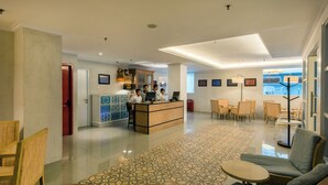 A hotel lobby with a reception desk, seating area, and a patterned carpet. - Yans House Hotel Bali (Kuta)