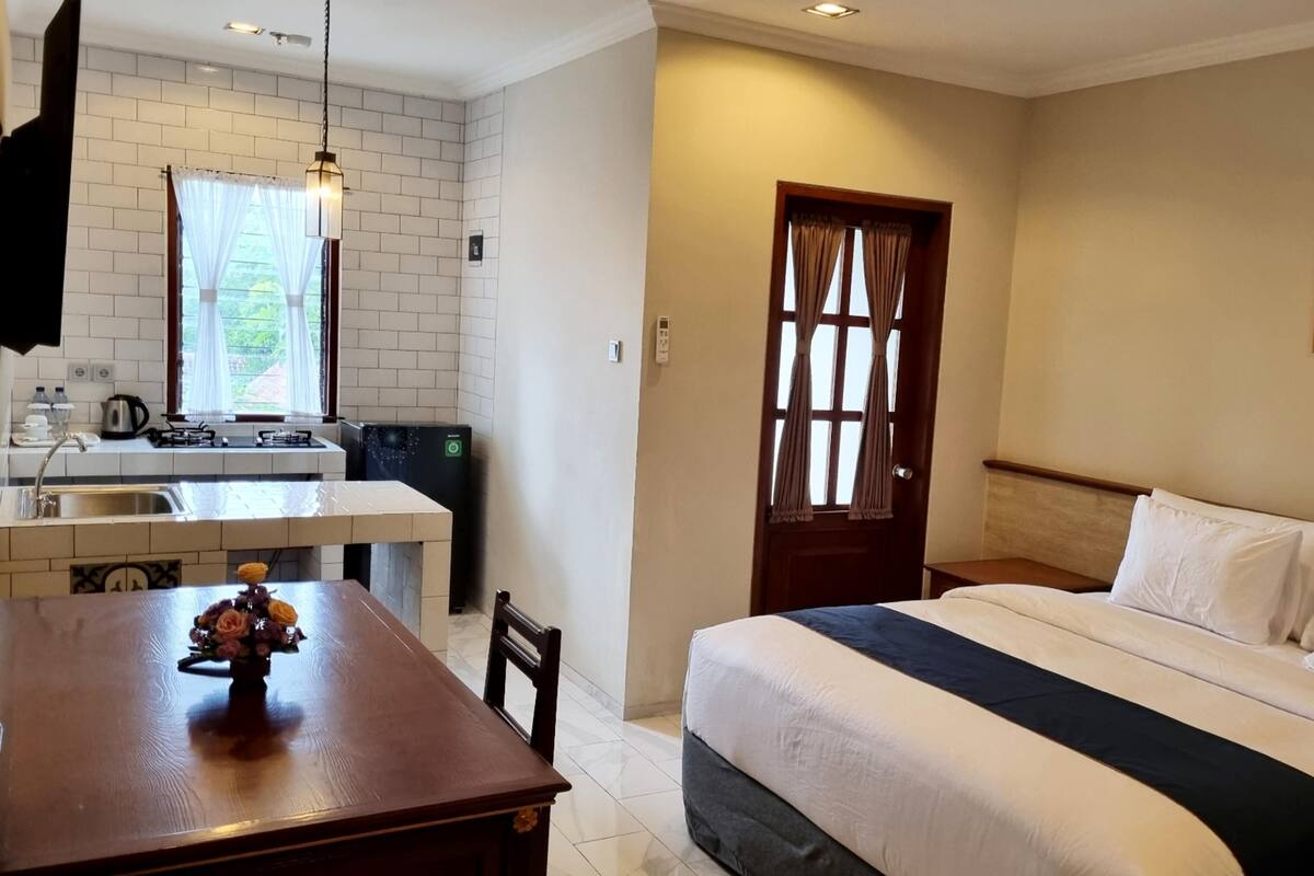 Ein Hotelzimmer mit Bett, Schreibtisch, Küchenzeile und einer Tür.