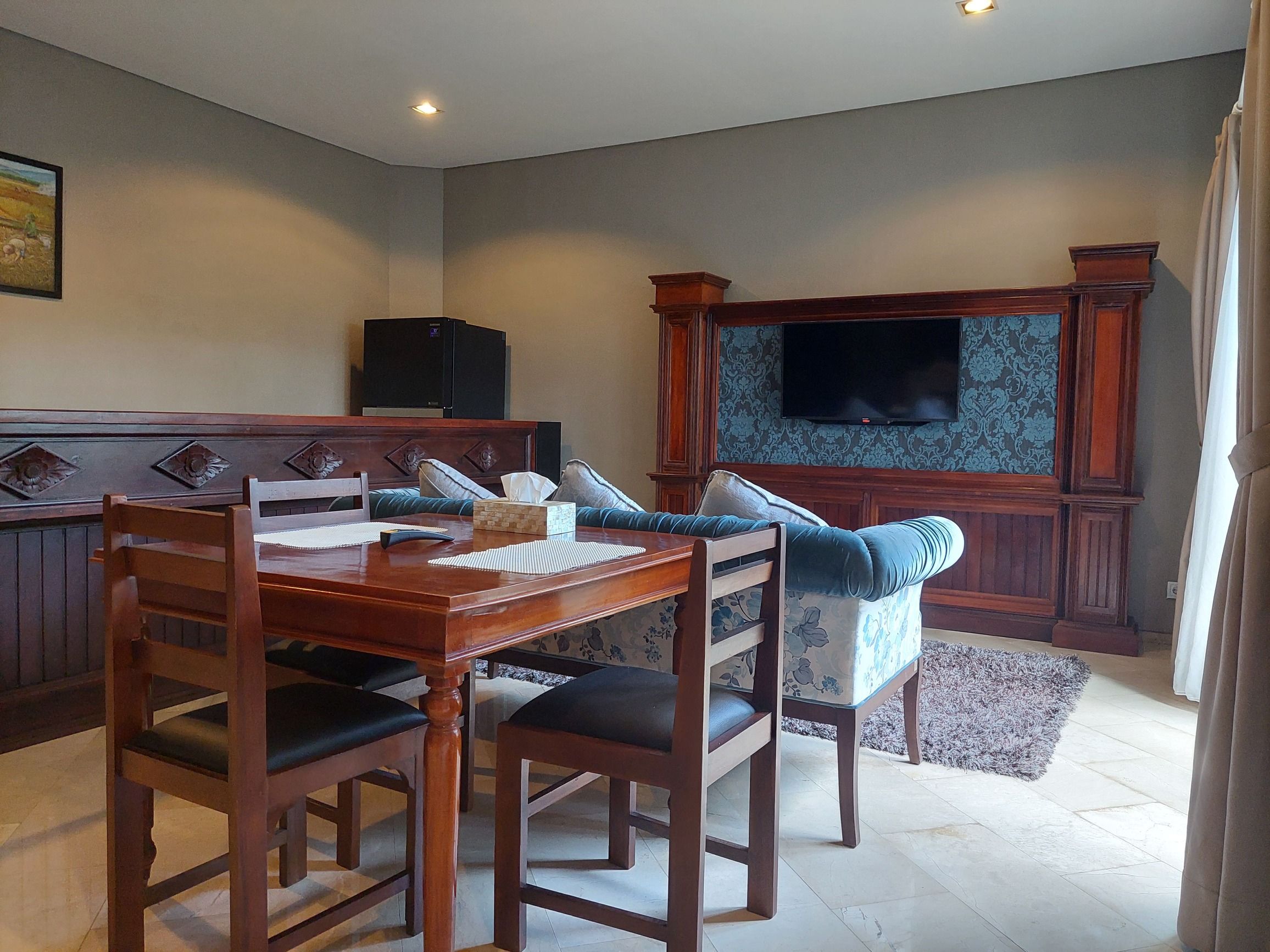 Un coin repas avec une table et des chaises en bois, un téléviseur et un mur décoré de motifs.