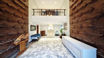 A spacious lobby with a high ceiling, a fireplace, a blue sofa, and a reception desk.