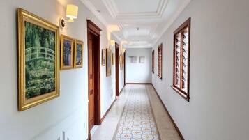 A hallway with framed artwork on the walls, a patterned floor, and a door with a wooden frame.