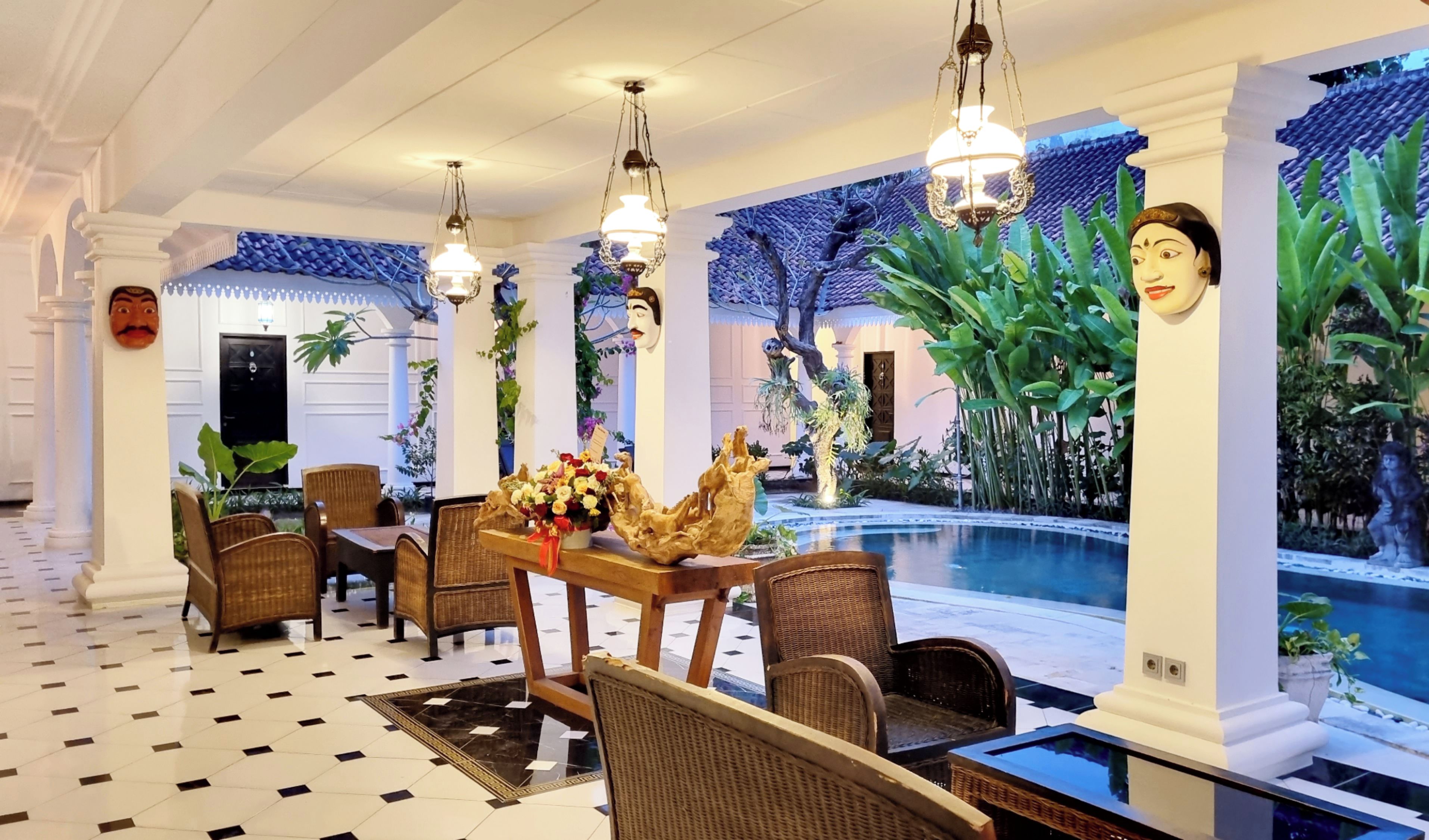 A dining area with wicker furniture, a pool, and tropical wall art.