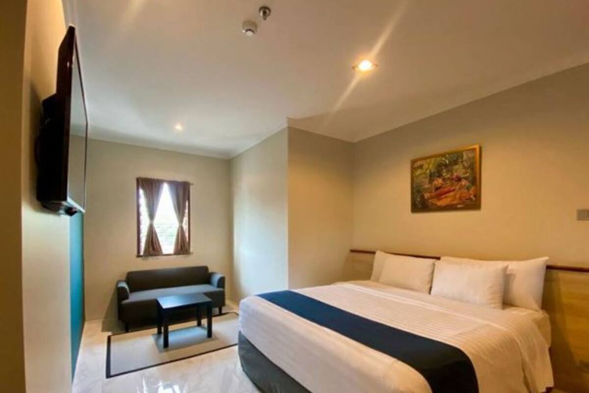 Ein Hotelzimmer mit Bett, einer Couch, einem Fernseher und einem Gemälde an der Wand.